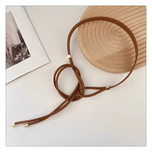 Brauner Ledergürtel mit goldenen Akzenten auf hellem Hintergrund, modisches Accessoire.