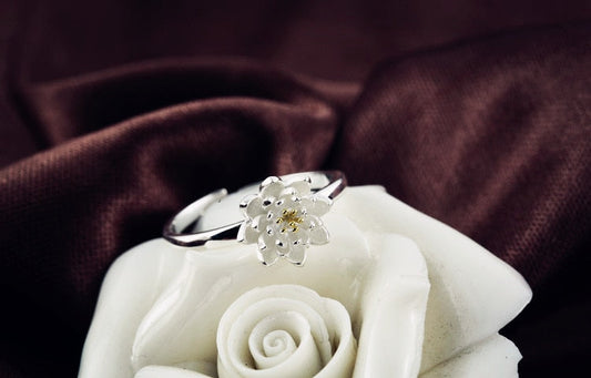 Silberner Lotusblumen-Ring auf weißer Rosenfigur, eleganter Schmuck, Damenaccessoire.
