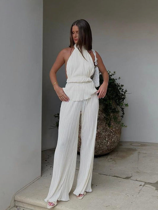 Frau in weißem, ärmellosem Jumpsuit aus Plissee-Stoff, elegantes Sommeroutfit, Mode-Trend.