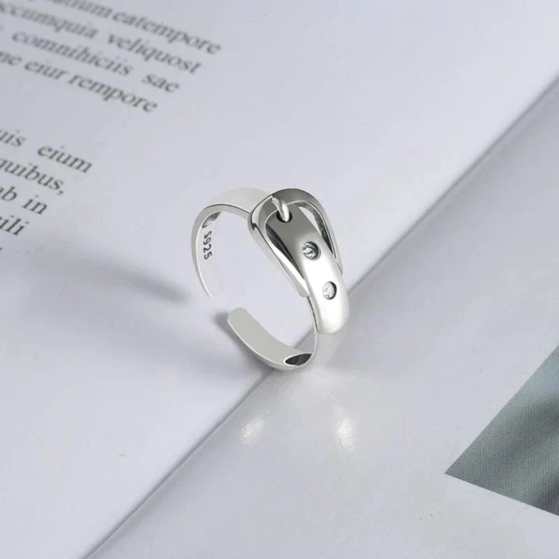 Silberner verstellbarer Ring mit zwei Zirkonia-Steinen auf offenem Buch, minimalistisches Design.