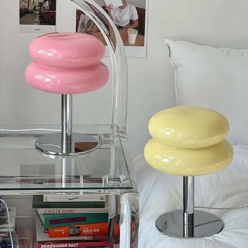 Rosa und gelbe Macaron-Tischlampen auf Glasnachttisch, modernes Design, Schlafzimmerdekoration.