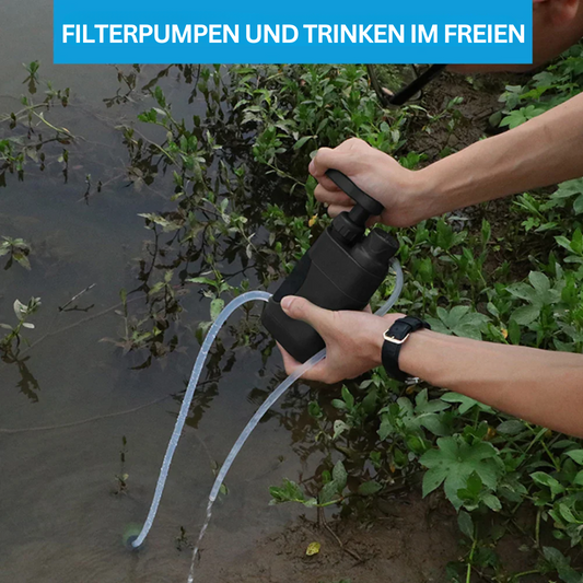 Person nutzt tragbare Wasserfilterpumpe am Flussufer, Outdoor-Trinkwasseraufbereitung.