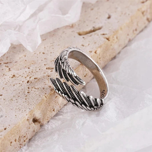 Silberner Ring mit Federdesign auf hellem Hintergrund, Schmuck, Accessoire, Geschenkidee.