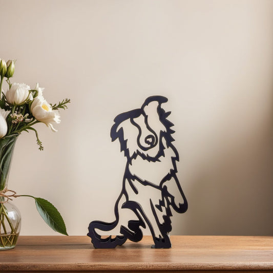 Metallskulptur Australian Shepherd, schwarz, auf Holzregal, neben Blumenstrauß in Vase.