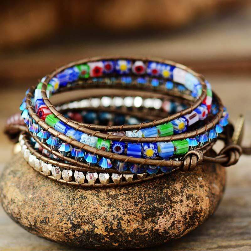 Handgemachtes Boho-Wickelarmband mit bunten Perlen und Blumenmuster auf Stein.