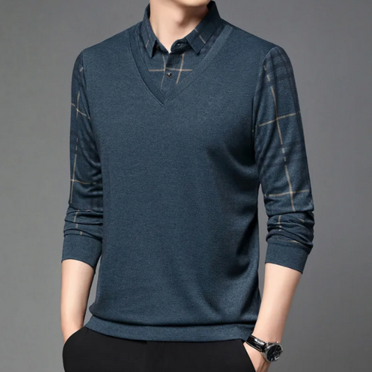 Mann in blauem V-Ausschnitt-Pullover mit karierten Ärmeln, Hemdkragen, grauer Hintergrund.