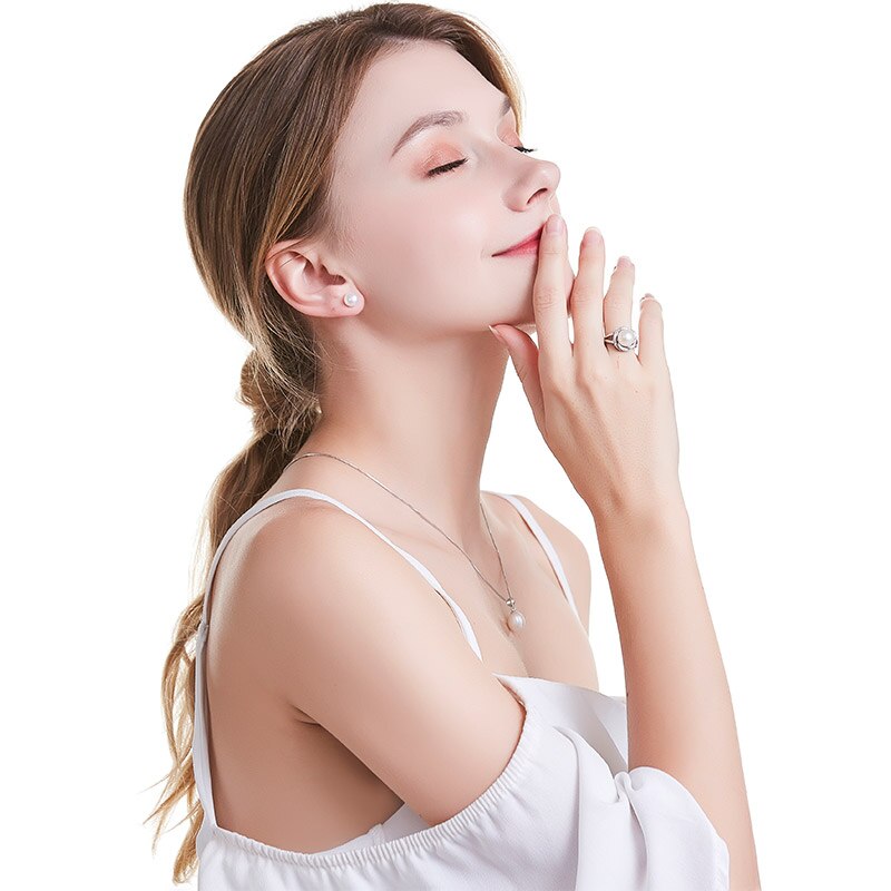 Frau mit Perlenohrringen, Silberkette und Ring, eleganter Schmuck, weißes Kleid, seitliches Profil.