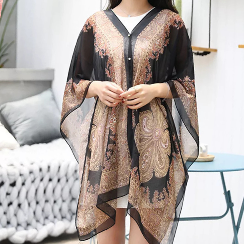 Frau trägt schwarzes, transparentes Kaftan-Kleid mit goldenen Paisley-Mustern, elegant und modisch.