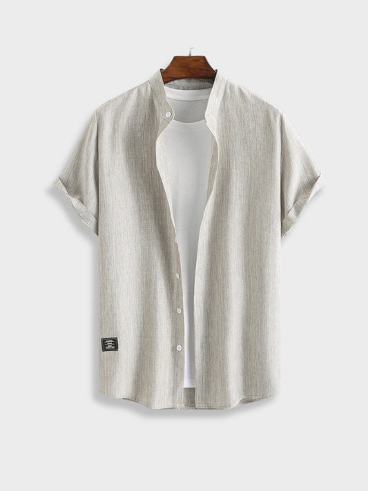 Hellgraues Leinenhemd für Herren, kurzärmelig, lässig, mit Knopfleiste, auf Holzkleiderbügel.