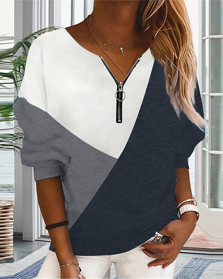 Frau in modischem, dreifarbigem Pullover mit Reißverschluss, lässiger Stil, Wohnzimmer-Hintergrund.