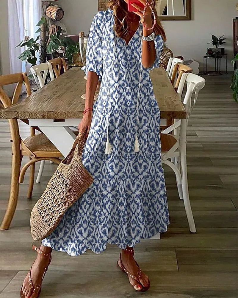 Frau in blau-weißem Boho-Kleid mit Strohtasche, steht in modernem Esszimmer.