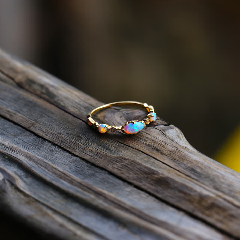 Goldener Opalring mit bunten Edelsteinen auf Holzoberfläche, eleganter Schmuck, Damenaccessoire.