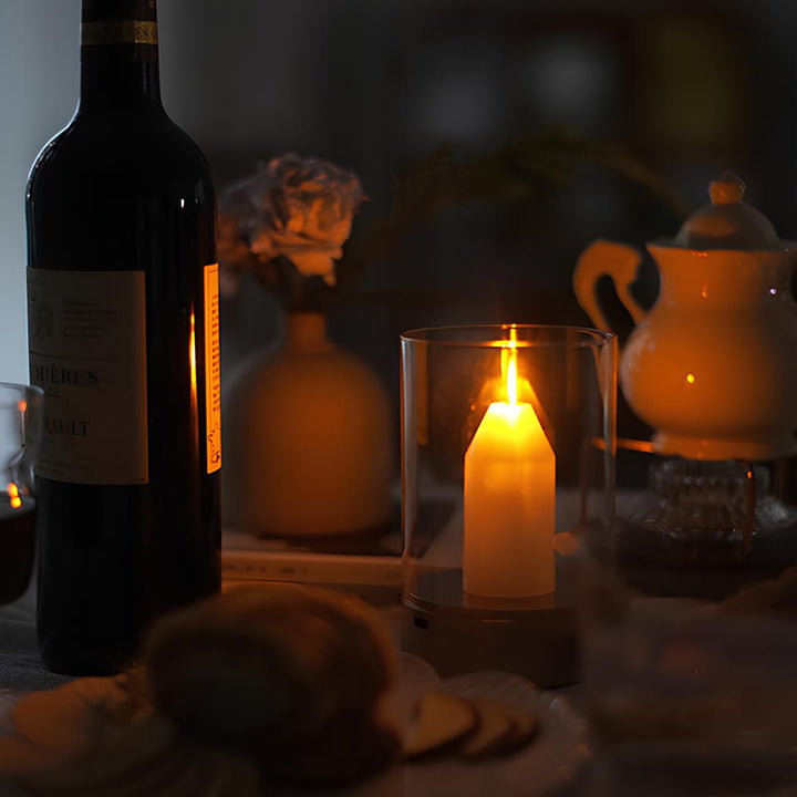 Kerzenlicht-Dekoration mit Weinflasche, Teekanne und Blumen auf einem Tisch.