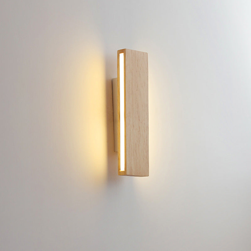 Svislá dřevěná lampa z boku, světelný pruh na boční straně září a osvětluje zeď. 10