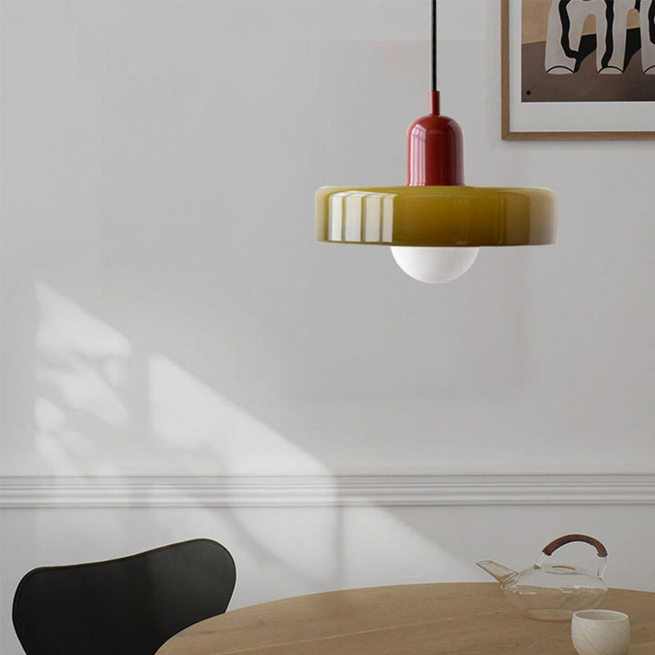 Rote und gelbe Pendelleuchte aus Glas über Holztisch, modernes Innendesign.