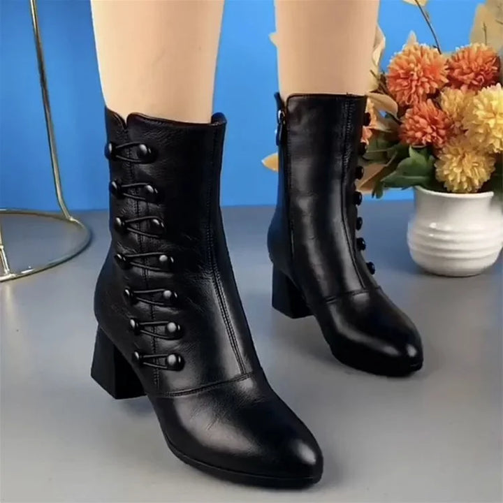 Schwarze Damenstiefeletten aus Leder mit Absatz, Schnürung, Herbstmode, vor Blumenarrangement.