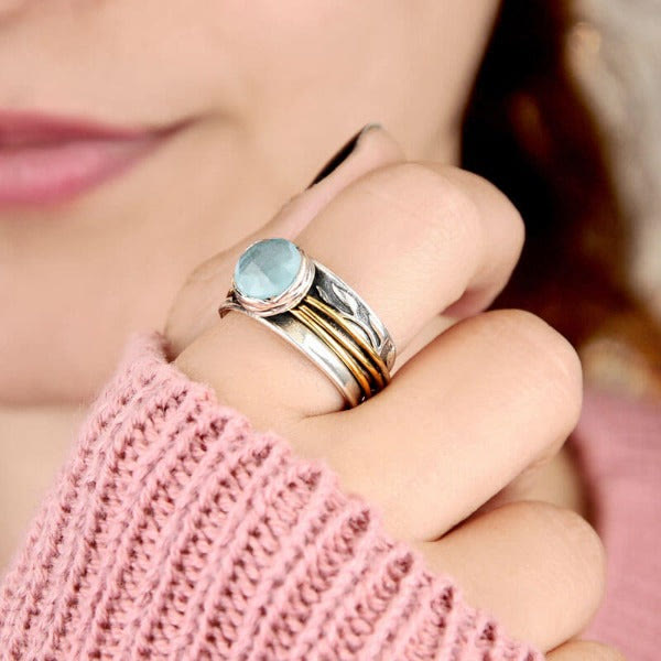 Frau trägt silbernen Ring mit blauem Edelstein, modisches Accessoire, Nahaufnahme.