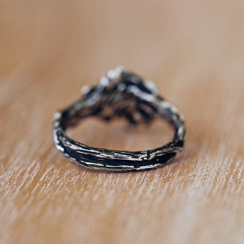 Silberner Vintage-Ring mit rustikalem Design auf Holzoberfläche, handgefertigter Schmuck.