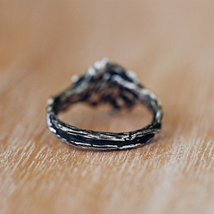 Silberner Vintage-Ring mit rustikalem Design auf Holzoberfläche, handgefertigter Schmuck.