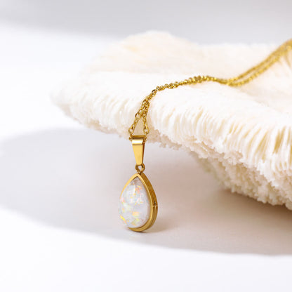 Goldene Halskette mit Opal-Anhänger auf weißem Hintergrund, eleganter Schmuck für Damen.
