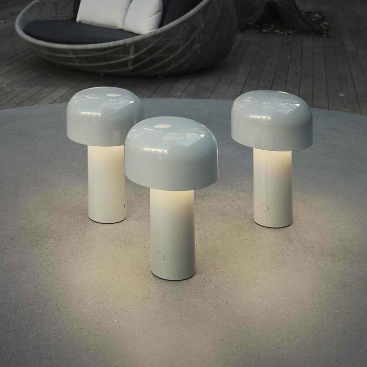 Drei weiße LED-Tischlampen im Freien auf grauem Tisch, modernes Design, stimmungsvolle Beleuchtung.