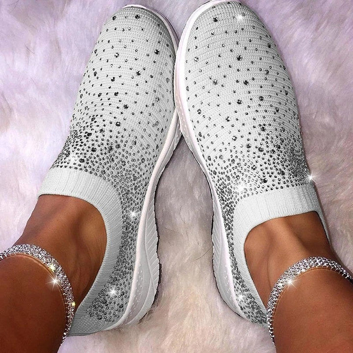 Weiße Damen-Sneaker mit Strasssteinen, bequem, modisch, auf flauschigem Teppich.