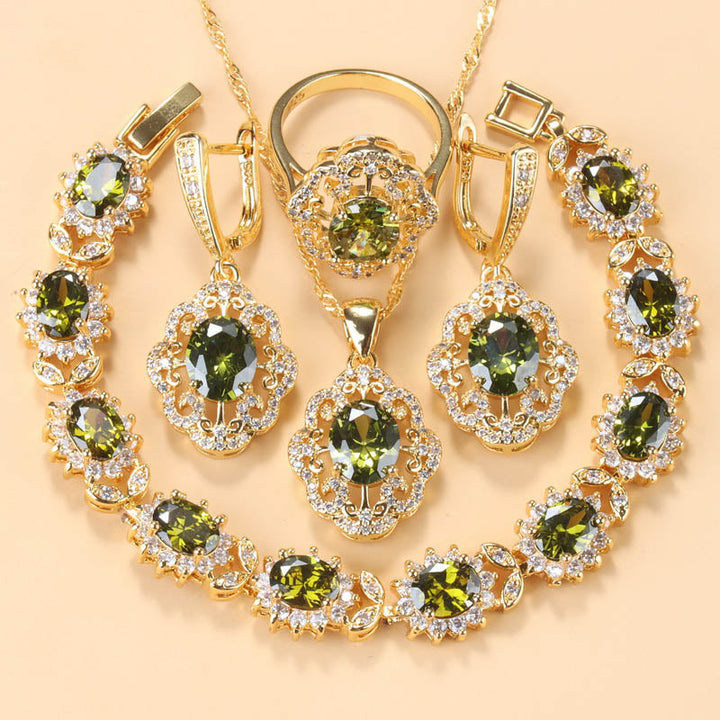 Goldene Schmuckset mit olivgrünen Zirkonia, bestehend aus Armband, Ring, Ohrringen und Anhänger.