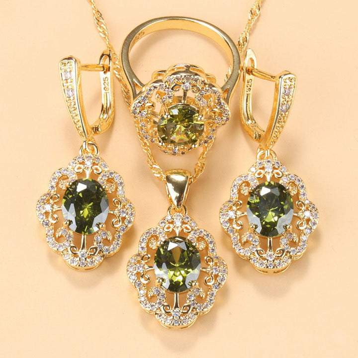 Goldene Schmuckset mit olivgrünen Zirkonia, bestehend aus Armband, Ring und Ohrringen.