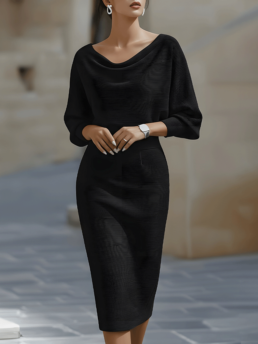 Modelka na dlážděné ulici v černé žebrované variantě šatů s netopýřími rukávy, pohled zepředu. 1