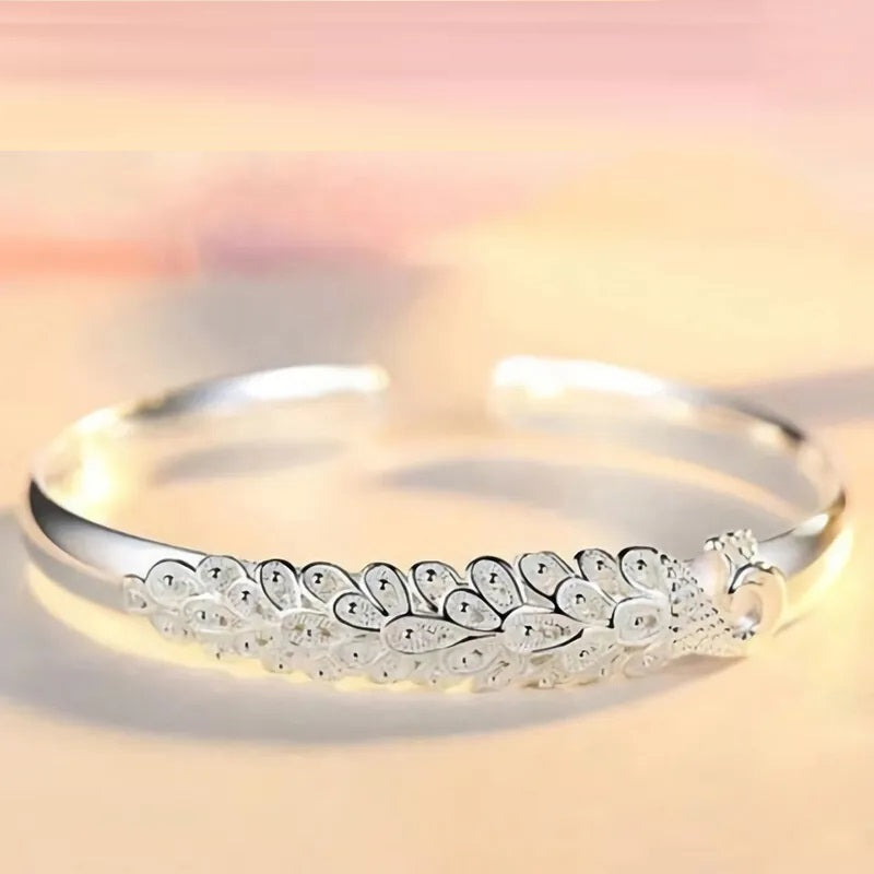 Silbernes Armreif mit Pfauenmotiv, elegantes Schmuckdesign, Damenaccessoire, Geschenkidee.