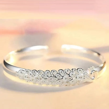 Silbernes Armreif mit Pfauenmotiv, elegantes Schmuckdesign, Damenaccessoire, Geschenkidee.