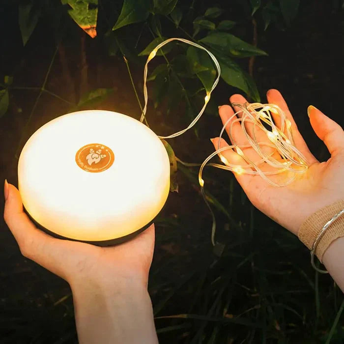 Tragbare LED-Lampe und Lichterkette, warmweiß, für Outdoor-Camping, in Händen gehalten.