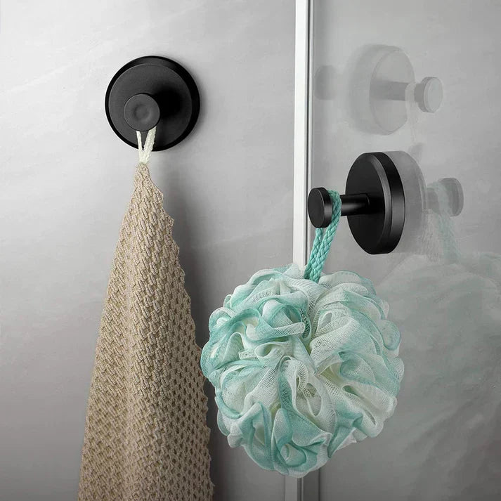 Schwarzer Wandhaken mit beigem Handtuch und mintgrünem Duschschwamm im Badezimmer.