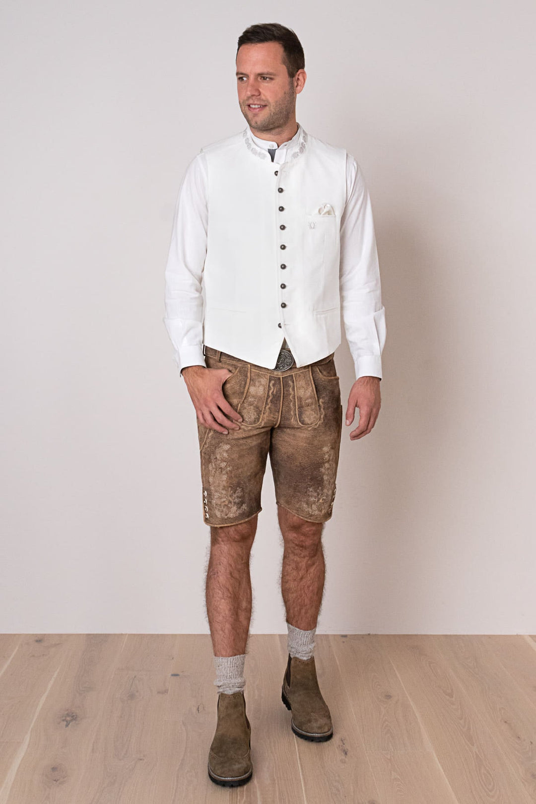 Mann in traditioneller Lederhose und weißer Weste, bayerische Tracht, Trachtenmode Herren.