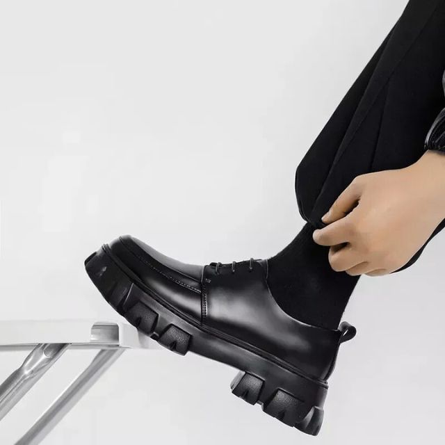Schwarzer Leder-Brogue mit dicker Sohle, Herrenmode, eleganter Schuh, seitliche Ansicht.