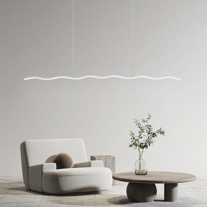 Moderne LED-Hängelampe, wellenförmig, weiß, über minimalistischem Wohnzimmer mit Sessel und Tisch.