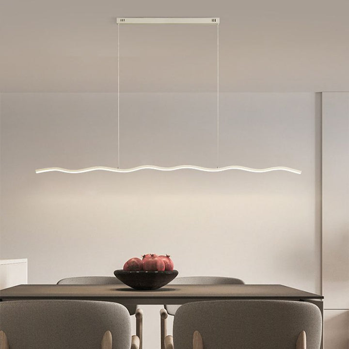 Moderne LED-Pendelleuchte über Esstisch, wellenförmig, minimalistisch, energiesparend, weiß.