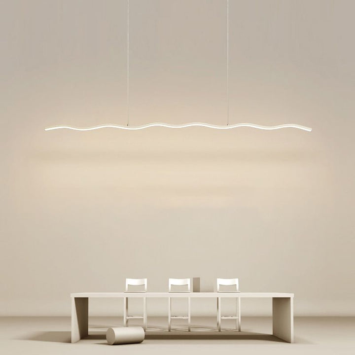 Moderne LED-Pendelleuchte, wellenförmig, über minimalistischem Esstisch mit weißen Stühlen.