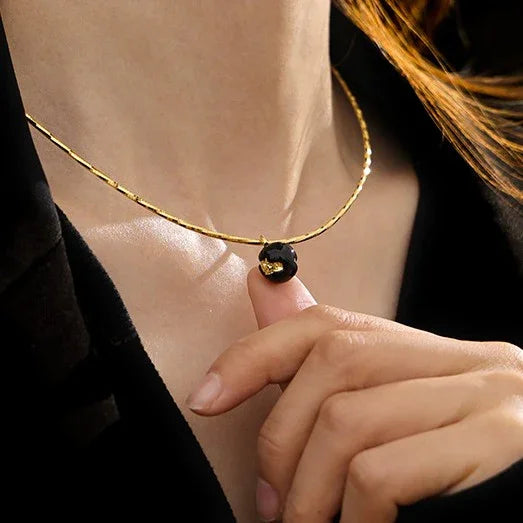 Goldene Halskette mit schwarzem Anhänger, eleganter Schmuck für Damen, modisches Accessoire.