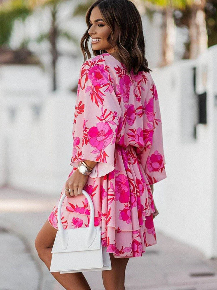 Frau in rosa Blumenkleid mit weißer Handtasche, lächelnd, draußen, modisch, Sommerkleidung.