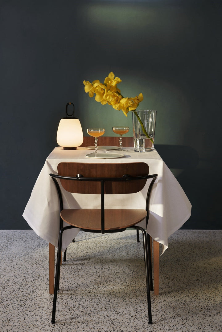 Moderner Esstisch mit weißer Tischdecke, gelben Blumen, Gläsern und Lampe, elegantes Design.