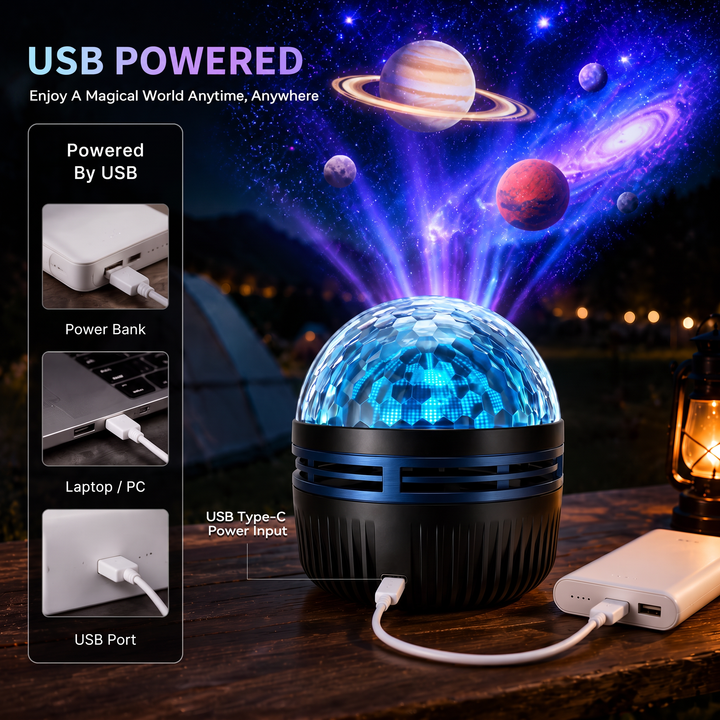 Černý kopulovitý projektor s modrým proužkem napájený kabelem USB-C z powerbanky na dřevěném stole, nad ním planety, vlevo další zdroje: notebook a nabíječka. 4