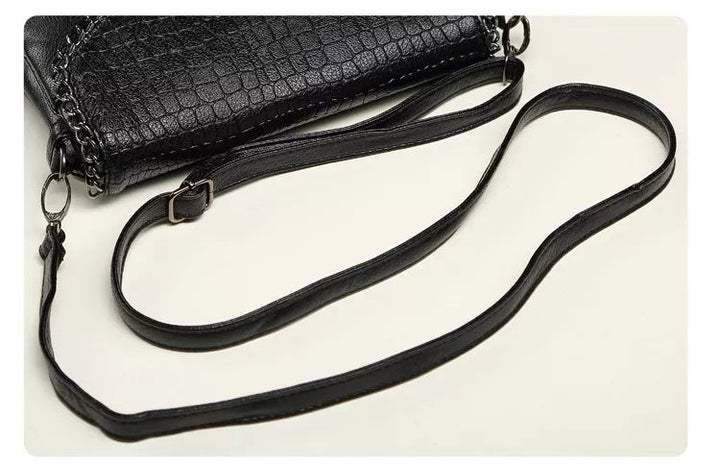 Schwarze Lederhandtasche mit Krokodilprägung und verstellbarem Schulterriemen.