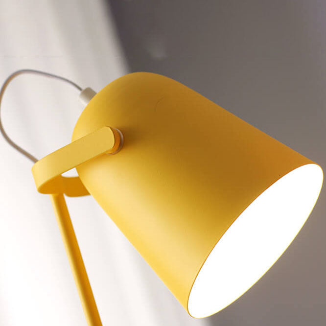 Detail žlutého kuželového stínidla lampy zespodu, vnitřek stínidla září bílým světlem, vidět je rameno uchycení a bílý kabel. 2