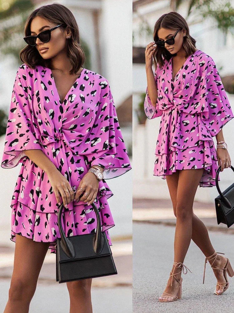Frau in rosa Leopardenkleid mit Sonnenbrille und schwarzer Handtasche, modisch, Sommeroutfit.