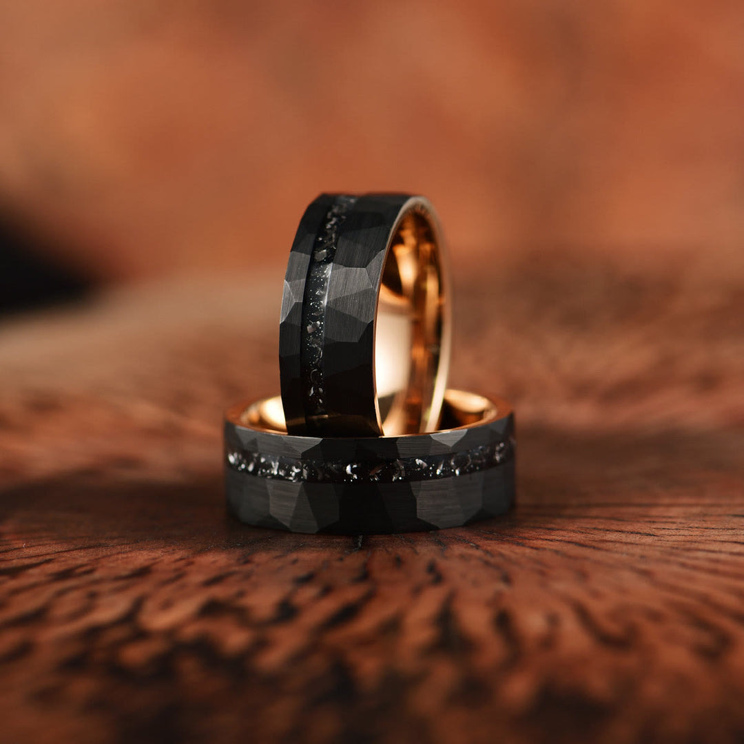 Zwei schwarze Wolframringe mit Diamanten auf Holzoberfläche, elegantes Schmuckdesign.