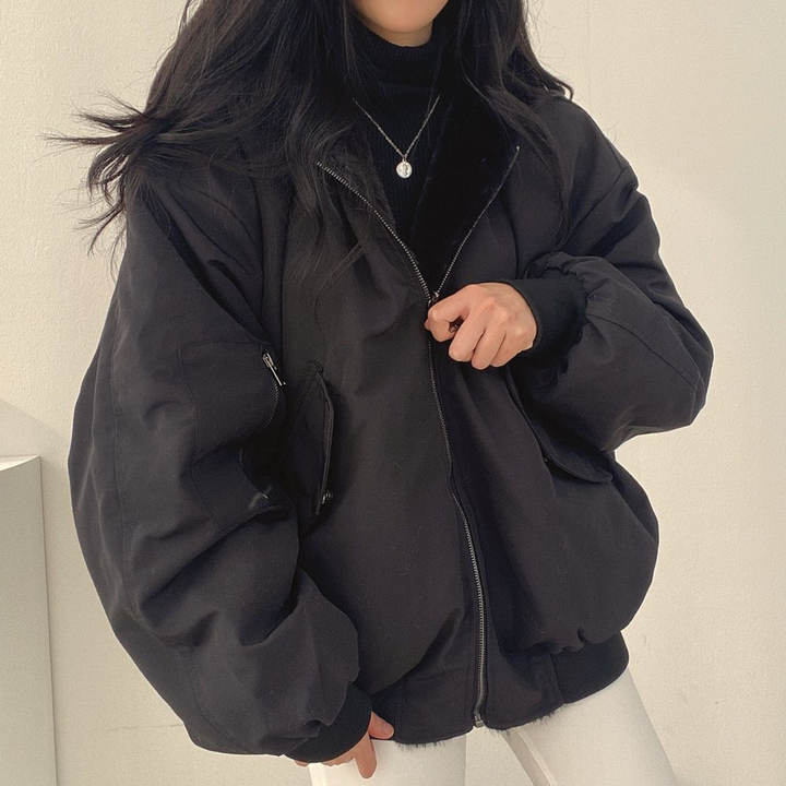 Frau in schwarzer Oversize-Jacke, Reißverschluss, modisch, Winterkleidung, lässiger Stil.