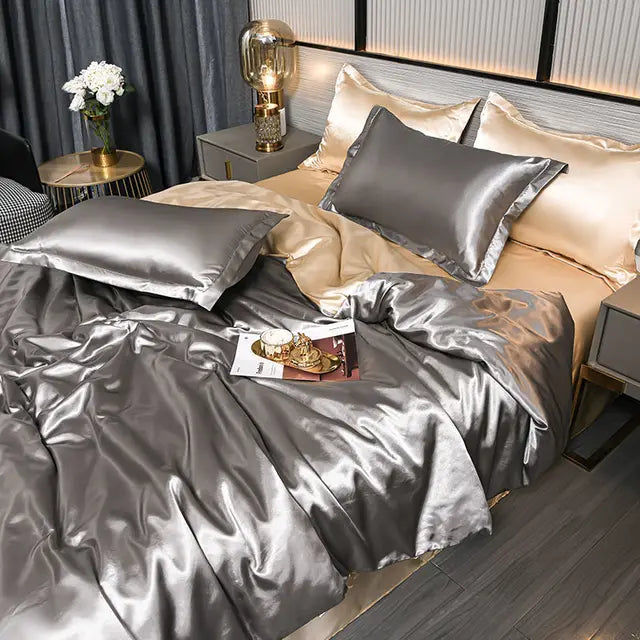 Luxuriöse silberne Satin-Bettwäsche-Set auf Doppelbett mit Kissen und Nachttischlampe.