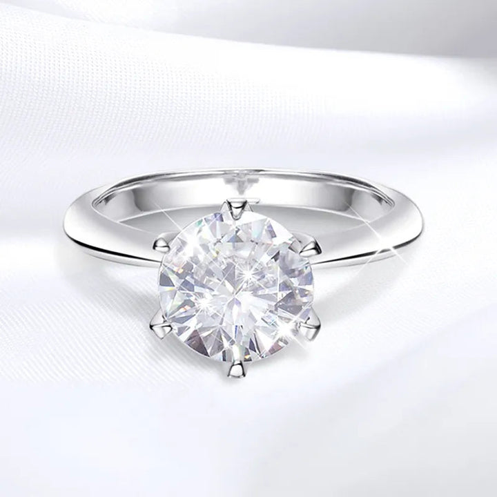 Silberner Verlobungsring mit großem, rundem Diamant auf weißem Hintergrund.