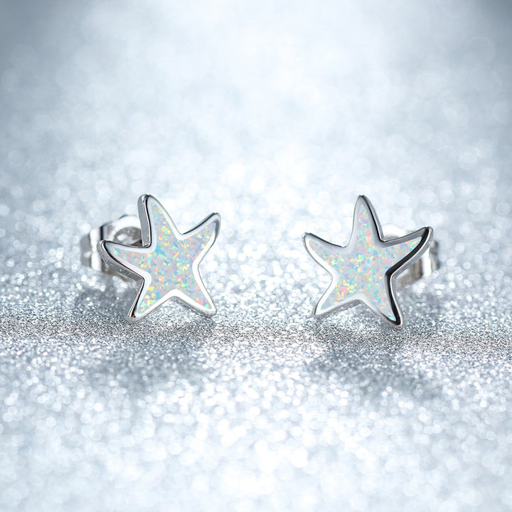 Silberne Stern-Ohrringe mit schimmerndem Opal-Design auf glitzerndem Hintergrund.